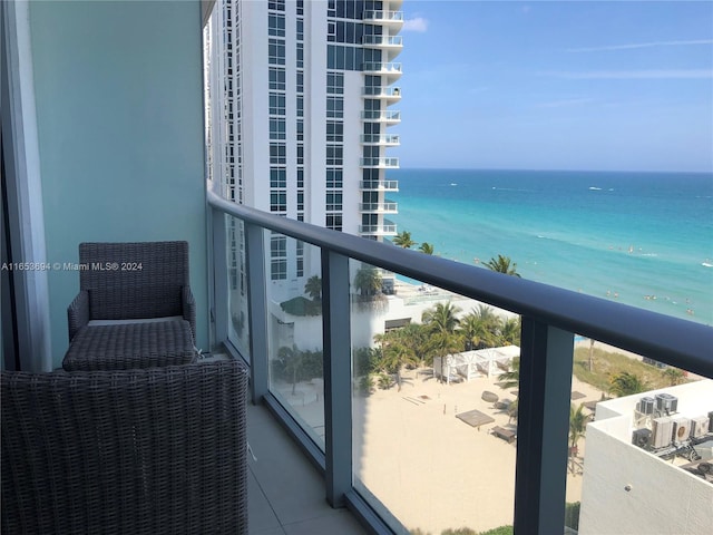 balcony featuring a view of the beach and a water view