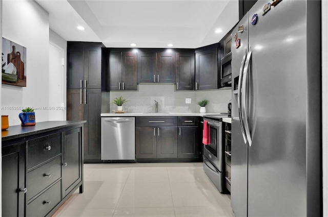 kitchen featuring dark brown cabinets, sink, light tile patterned flooring, appliances with stainless steel finishes, and tasteful backsplash