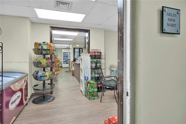 corridor featuring light hardwood / wood-style floors and a paneled ceiling