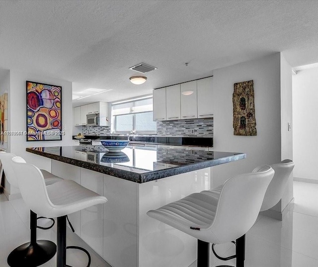 kitchen with tasteful backsplash, white cabinets, and a kitchen breakfast bar