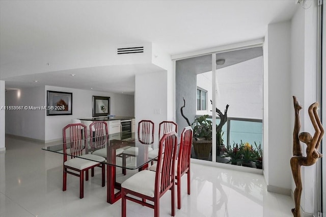 dining space featuring light tile patterned floors, wine cooler, and floor to ceiling windows