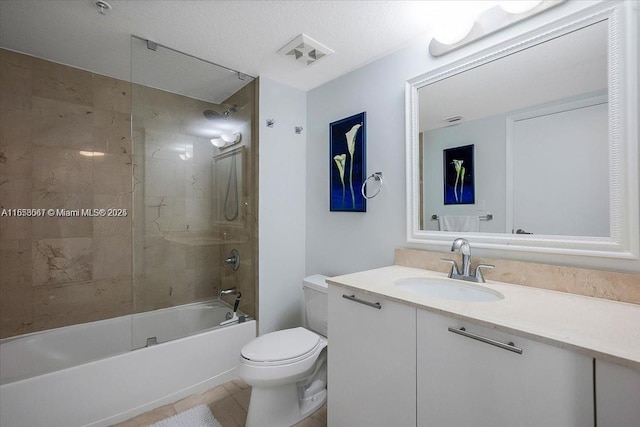 full bathroom featuring vanity, tile patterned floors, tiled shower / bath combo, toilet, and a textured ceiling