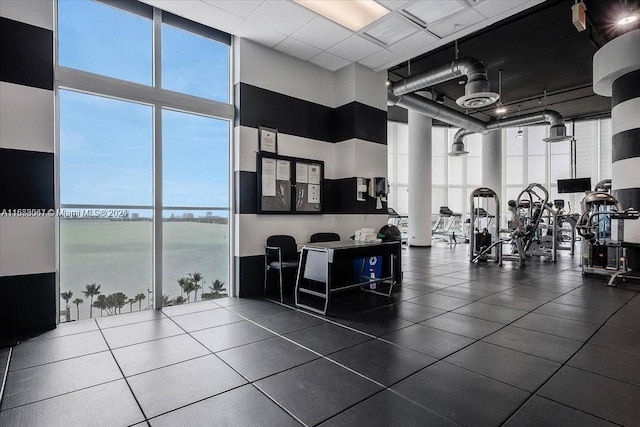 interior space with a high ceiling, a water view, and floor to ceiling windows