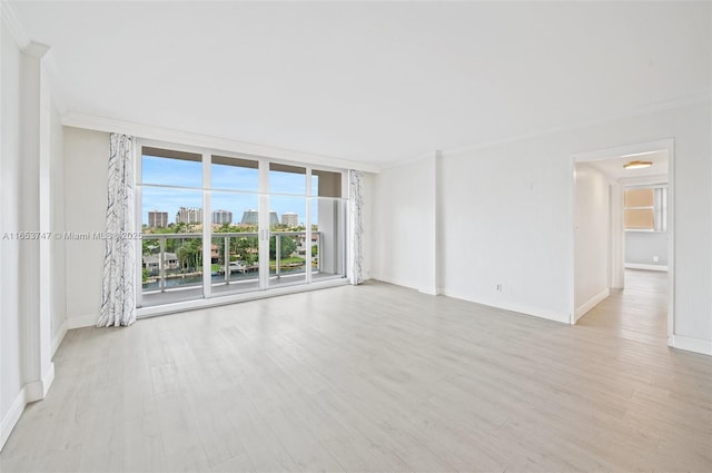 unfurnished room featuring light wood-type flooring, expansive windows, and crown molding