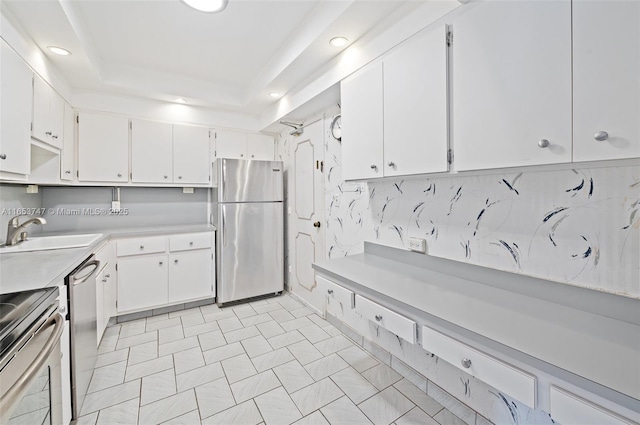 kitchen featuring white cabinets, stainless steel appliances, a raised ceiling, and sink