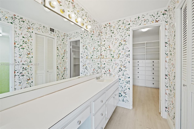 bathroom featuring hardwood / wood-style flooring, crown molding, and vanity