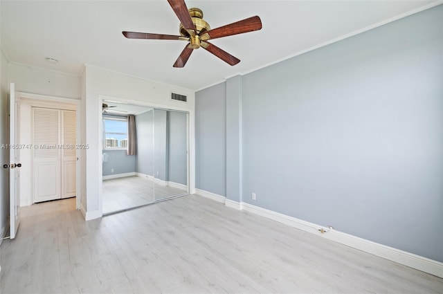 unfurnished bedroom featuring ceiling fan, ornamental molding, light hardwood / wood-style floors, and a closet