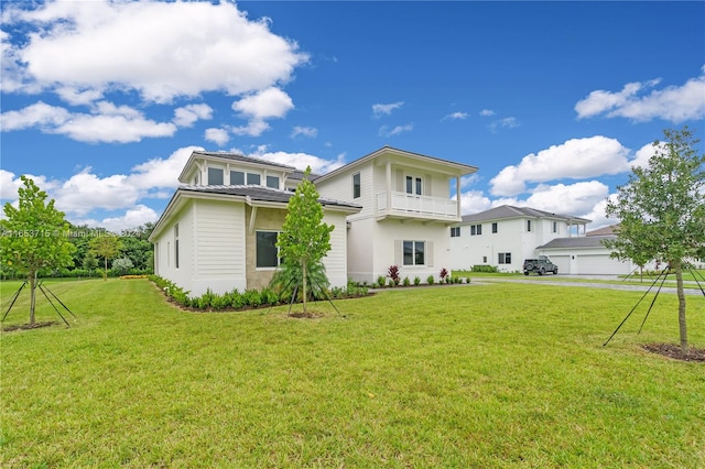 back of house with a yard, a garage, and a balcony