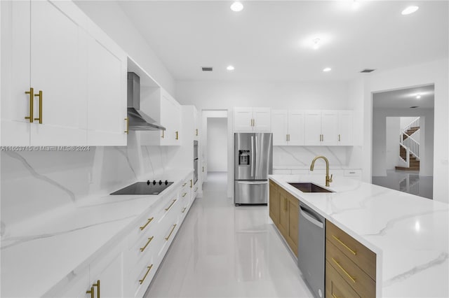 kitchen with appliances with stainless steel finishes, sink, decorative backsplash, light stone counters, and wall chimney range hood