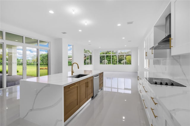 kitchen featuring black electric stovetop, sink, light stone countertops, and a wealth of natural light