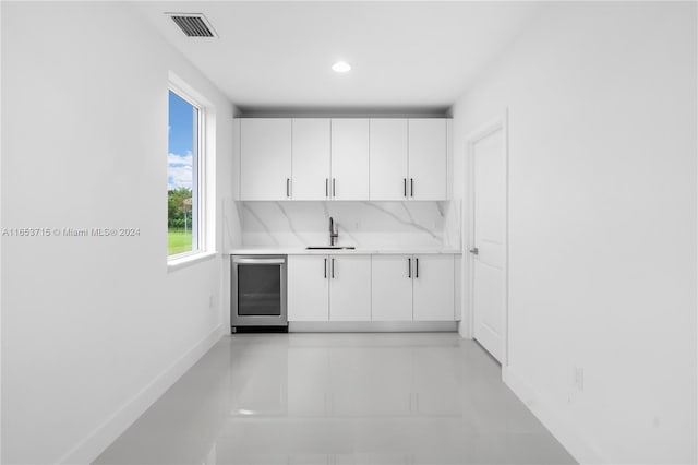 kitchen with white cabinets, tasteful backsplash, wine cooler, and sink