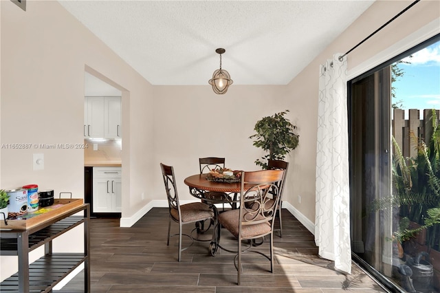 dining space with a textured ceiling and dark hardwood / wood-style floors