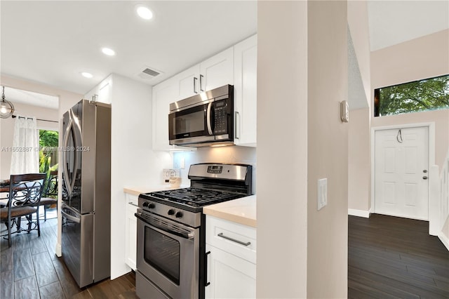 kitchen with stainless steel appliances, white cabinetry, and dark hardwood / wood-style flooring