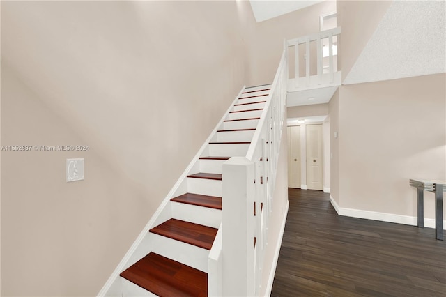 staircase with a towering ceiling and hardwood / wood-style flooring