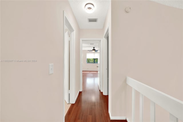 hallway with a textured ceiling and dark hardwood / wood-style floors