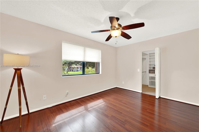 spare room featuring a textured ceiling, dark wood-type flooring, and ceiling fan