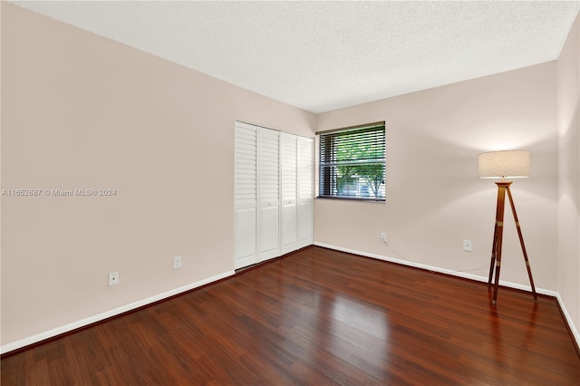 empty room featuring a textured ceiling and dark hardwood / wood-style floors