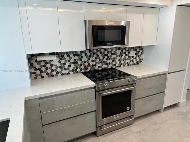 kitchen with light tile patterned flooring, appliances with stainless steel finishes, white cabinets, and tasteful backsplash