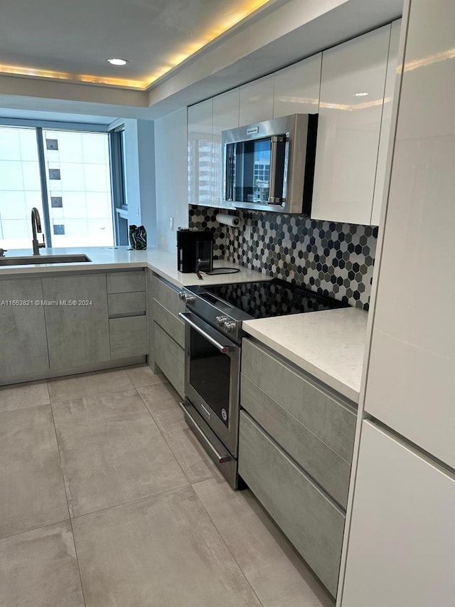 kitchen featuring appliances with stainless steel finishes, light stone countertops, tasteful backsplash, and sink