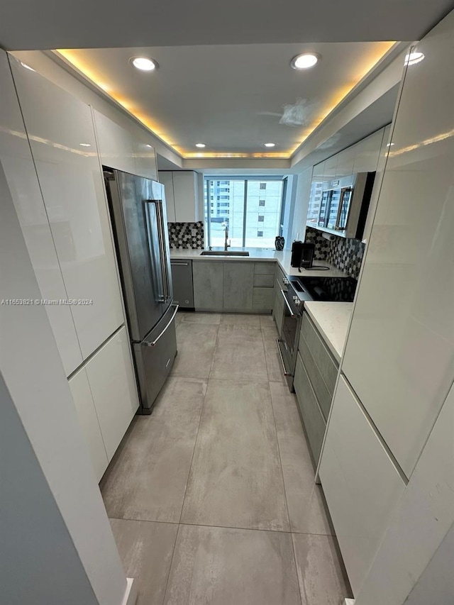 kitchen with stainless steel appliances, gray cabinetry, sink, and backsplash