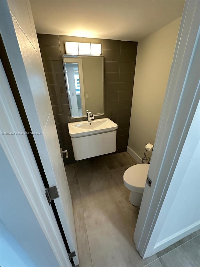 bathroom featuring vanity, toilet, and tile walls