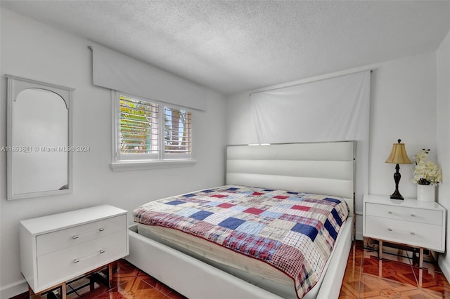 bedroom featuring parquet flooring and a textured ceiling