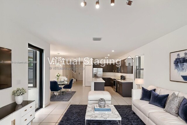 tiled living room with a notable chandelier