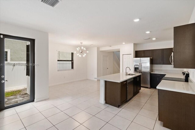 kitchen with pendant lighting, sink, a center island with sink, stainless steel appliances, and an inviting chandelier