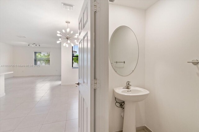 bathroom with sink, a chandelier, and tile patterned flooring