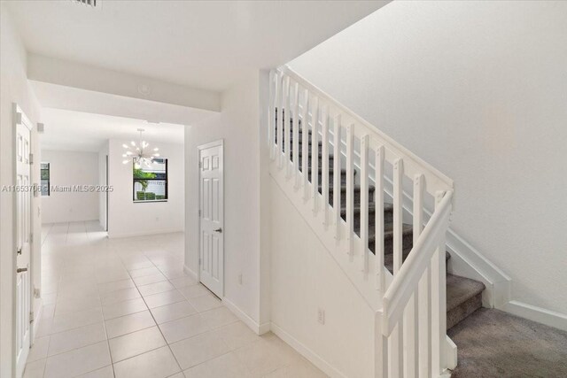 staircase featuring tile patterned floors and an inviting chandelier