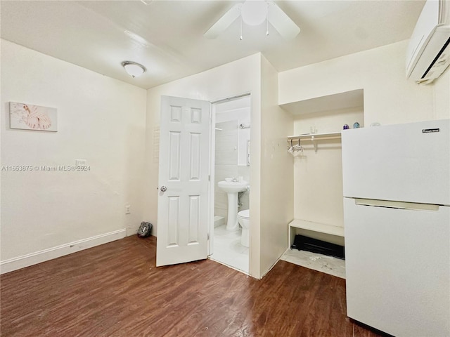 unfurnished bedroom with a closet, a wall mounted air conditioner, dark wood-type flooring, ceiling fan, and white refrigerator