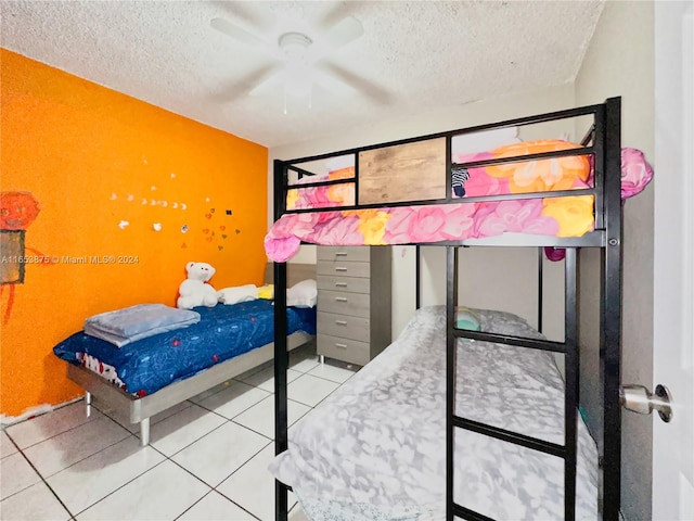 bedroom with ceiling fan, light tile patterned floors, and a textured ceiling