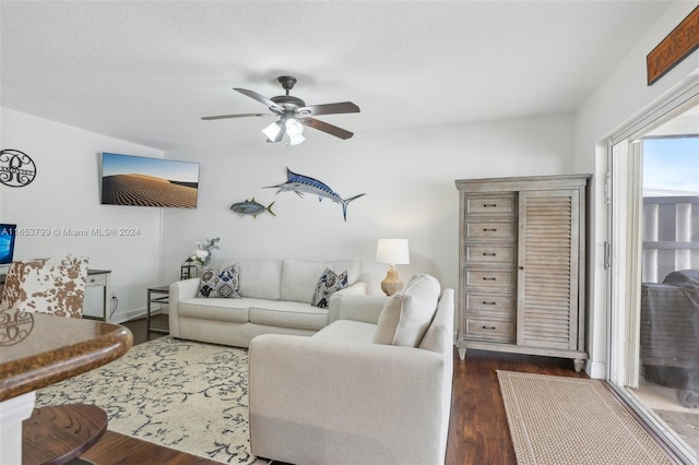 living room featuring dark wood-type flooring and ceiling fan