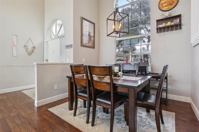 dining area with plenty of natural light, dark hardwood / wood-style floors, and an inviting chandelier