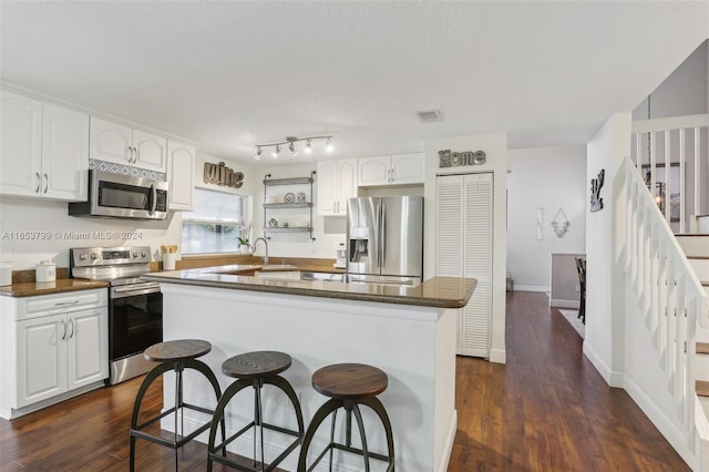 kitchen with a center island, stainless steel appliances, dark hardwood / wood-style floors, and white cabinetry