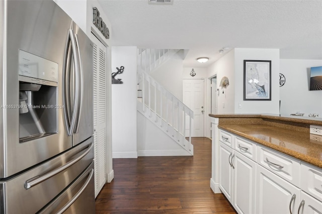 kitchen featuring stainless steel fridge, dark hardwood / wood-style floors, white cabinetry, and a textured ceiling