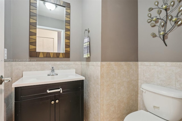 bathroom with tile walls, toilet, and vanity