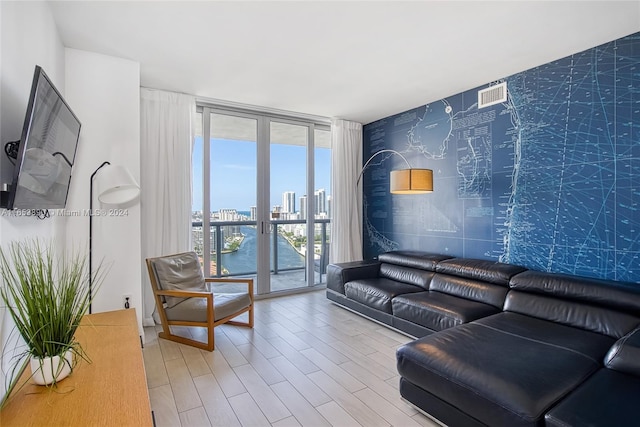 living room featuring light wood-type flooring, a wall of windows, and a water view