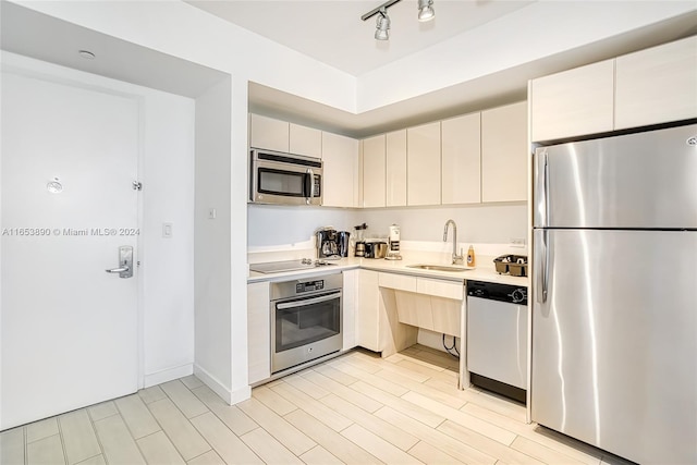 kitchen featuring light wood-type flooring, cream cabinets, stainless steel appliances, and sink