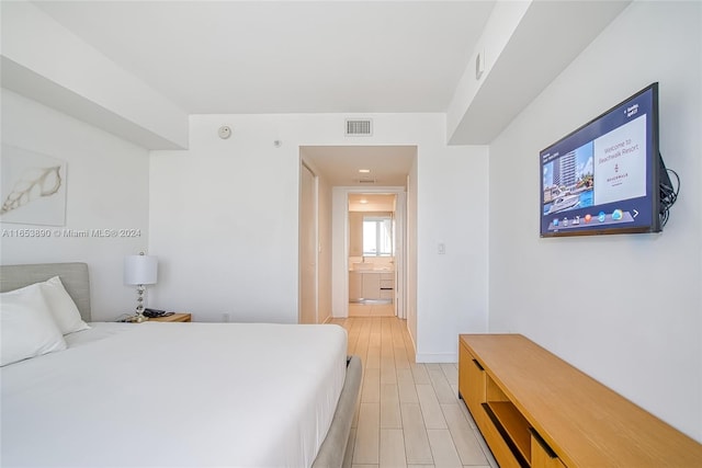 bedroom featuring ensuite bathroom and light hardwood / wood-style floors