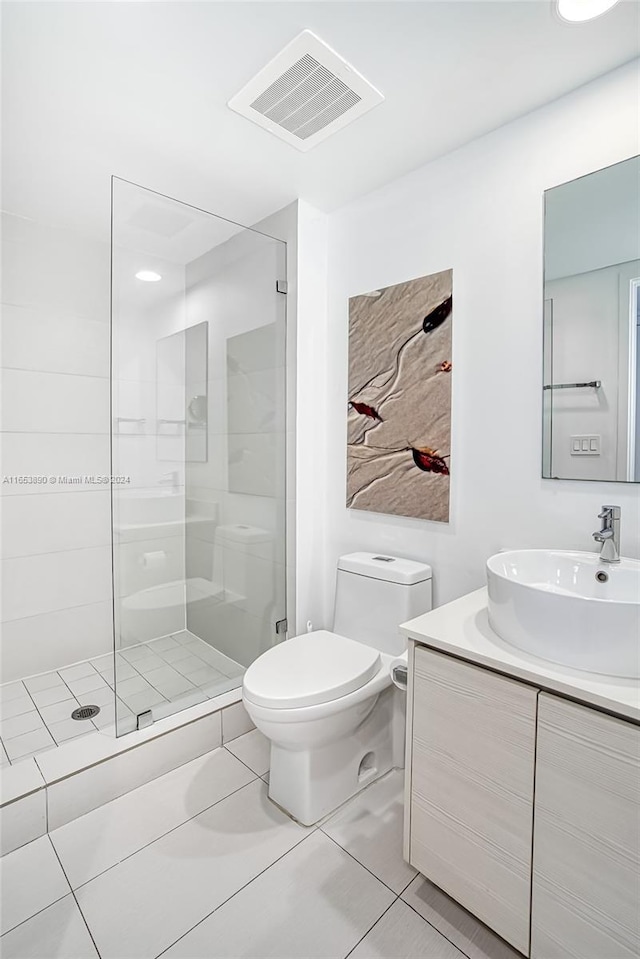 bathroom featuring tiled shower, tile patterned flooring, toilet, and vanity