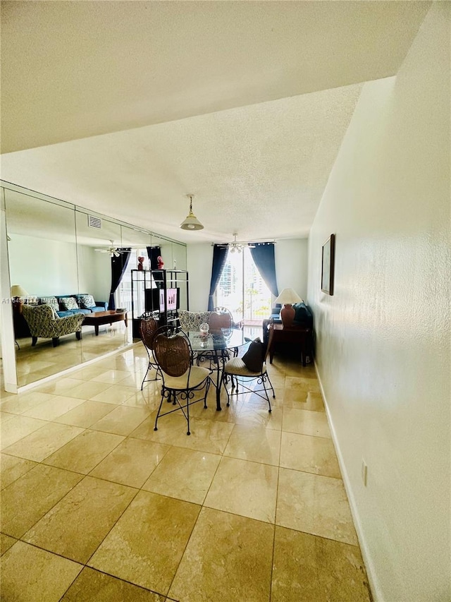 interior space with light tile patterned flooring, baseboards, and a textured ceiling