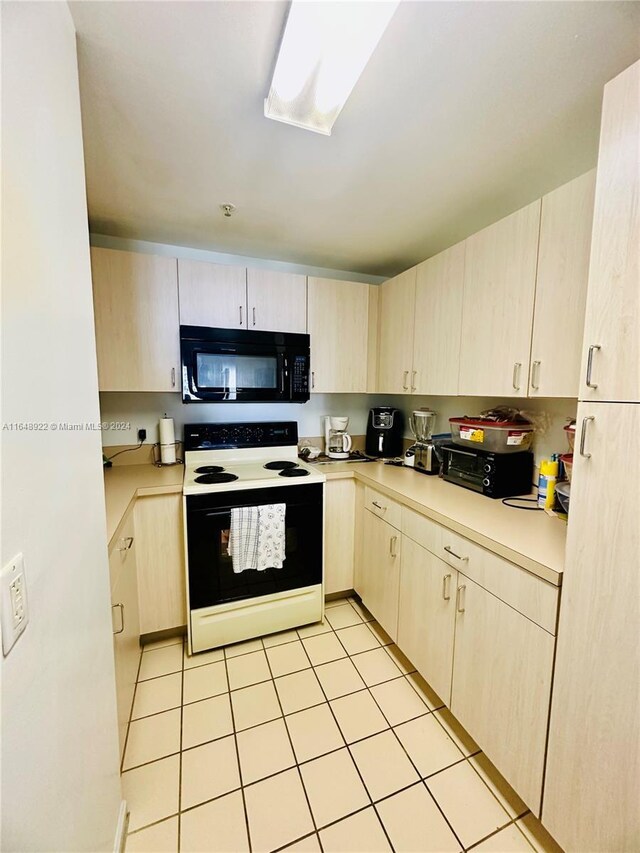 kitchen featuring light tile patterned flooring, light brown cabinets, and white electric range oven