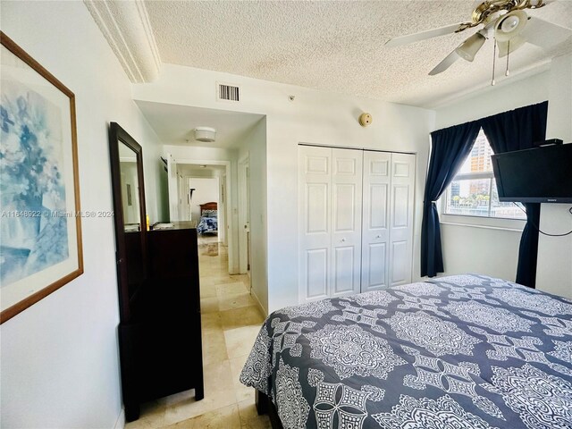 tiled bedroom featuring a textured ceiling, ceiling fan, and a closet