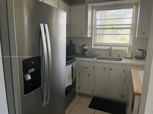 kitchen with white cabinets, sink, range, and stainless steel refrigerator with ice dispenser