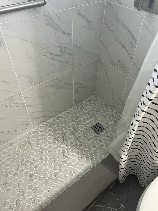 bathroom with a tile shower and marble finish floor