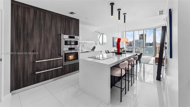 kitchen featuring a kitchen island, a kitchen breakfast bar, light tile patterned floors, and dark brown cabinetry