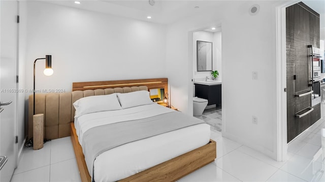 bedroom featuring ensuite bath, light tile patterned flooring, recessed lighting, and a sink