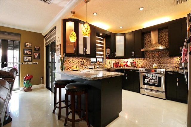 kitchen with stone counters, decorative light fixtures, electric range, sink, and wall chimney range hood