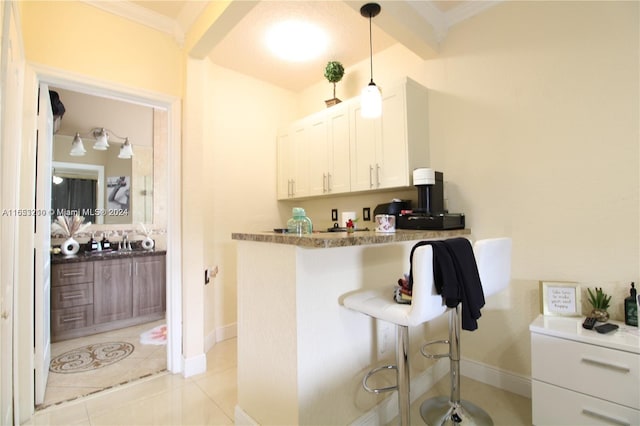 kitchen featuring white cabinets, hanging light fixtures, light tile patterned floors, and ornamental molding